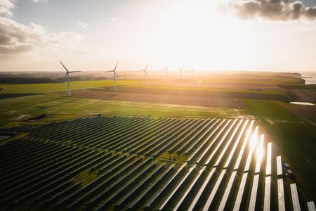 Weite Landschaftsaufnahe mit Windrädern udn PV Farm