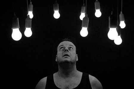 Ein Mann steht im dunklen, über ihm leichten einige LED Birnen von der Decke