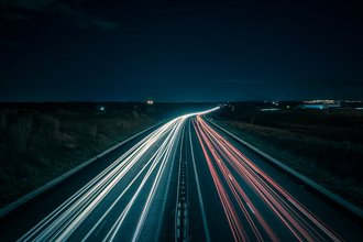 Zeitrafferfoto bei Nacht mit Lichtlinien von Autoscheinwerfern auf der Autobahn