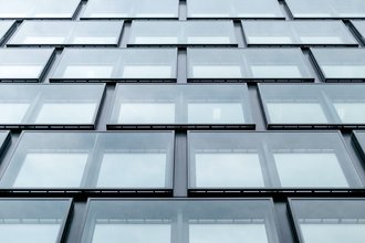 Fotoausschnitt einer komplett verglasten Fassade eines mehrstöckigen Bürogebäudes