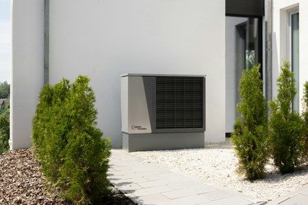 Photo of a heat pump in front of a new-build building