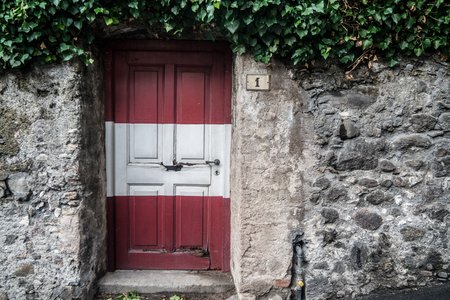 Tür eines alten Steinhauses in Österreich. Die Tür ist von oben nach unten mit den Bundesfarben rot -weiß - rot bemalt.