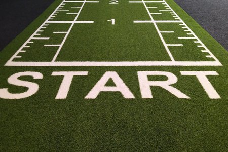 Foto eines grünen Läuferteppichs mit dem Wort Start und den Startmarkierungen